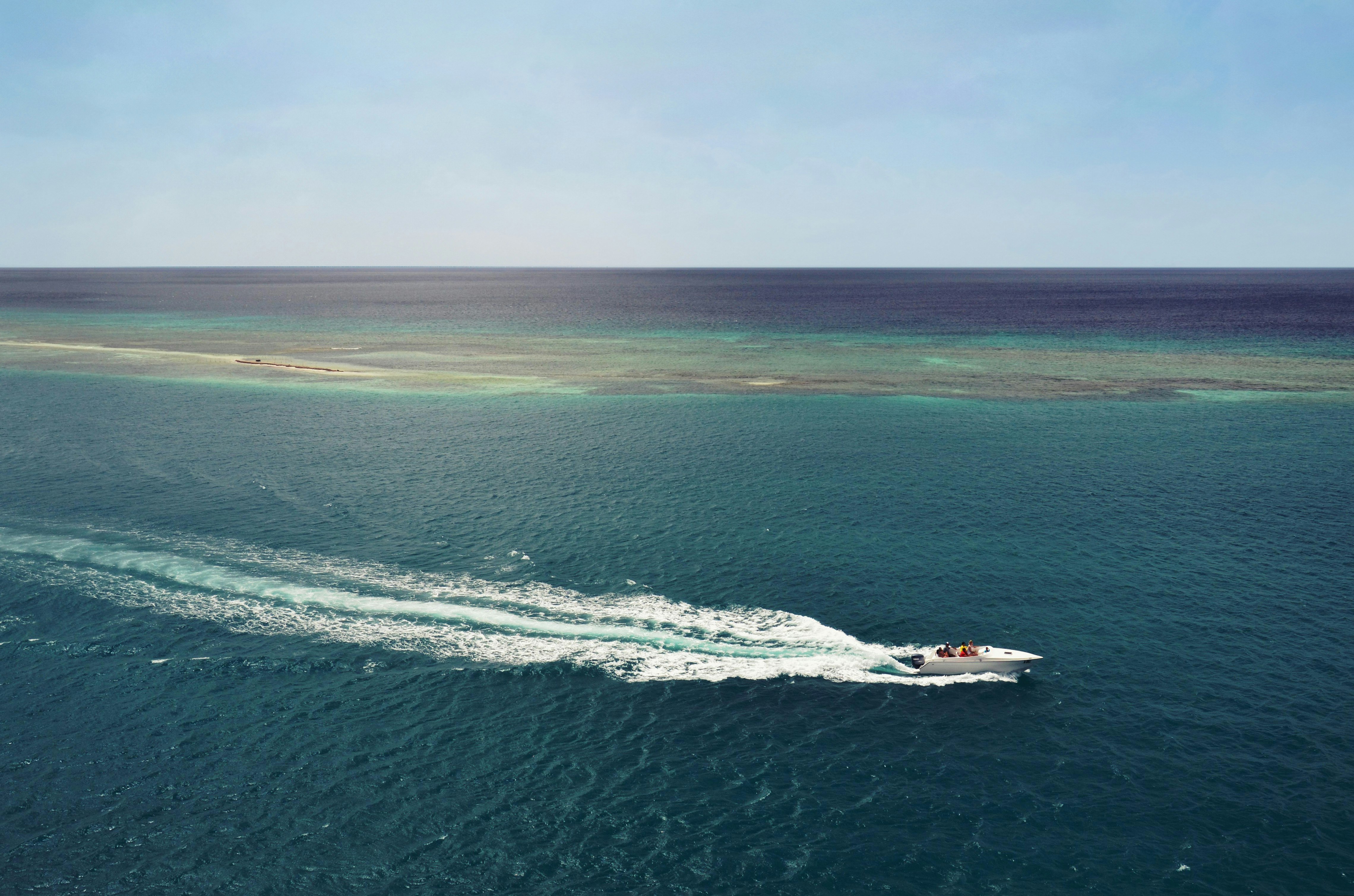 white speedboat running in middle of ocean during daytime